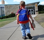 1st grade boy walking into school with backpack and lunch bag