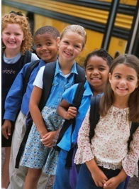 2nd grade girls standing by the school bus