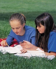 two girls studying together outside on the lawn