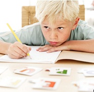 first grade boy with chin on his hand, doing schoolwork