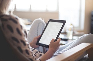 Female student reading on a kindle device from home