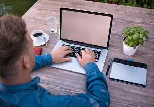 young man seated at a desk, working on a laptop