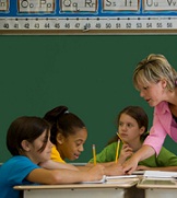 teacher helping students with worksheets