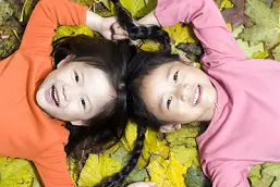 two girls in a pile of leaves