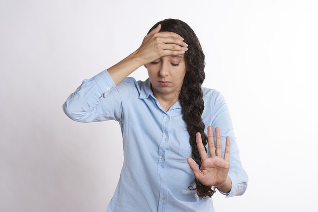 Stressed out young woman, holding her head and pushing her hand out in front of her